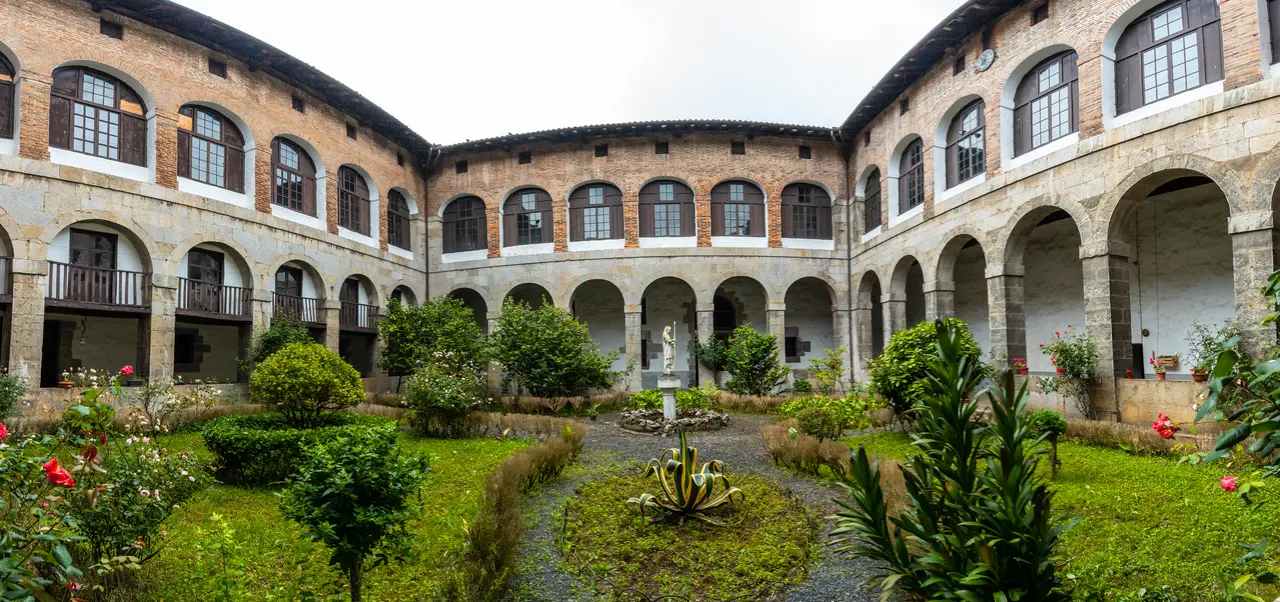 Historic college courtyard with arched corridors and gardens